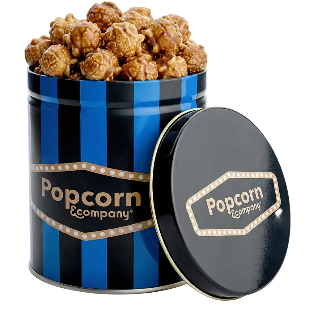 
                  
                    Caramel popcorn in a blue and black striped tin with 'Popcorn Company' branding.
                  
                
