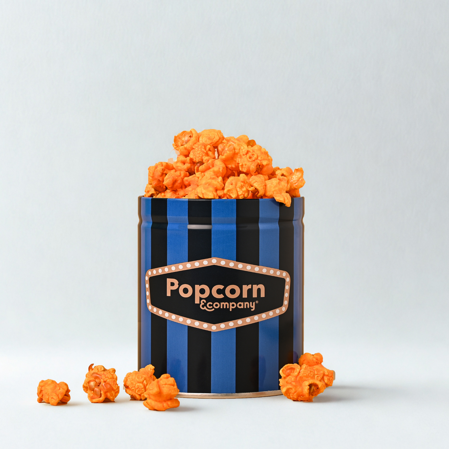 
                  
                    Blue popcorn container with cheesy siracha popcorn inside 
                  
                